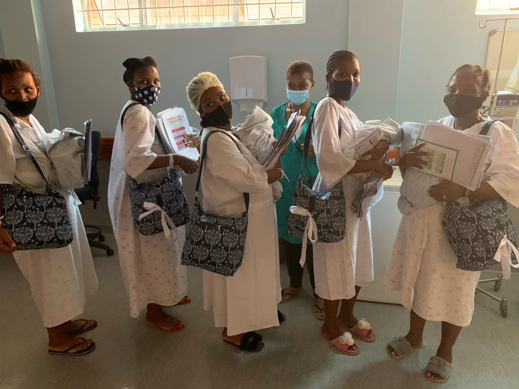 A packed nappy bag being handed to a mother with her newborn