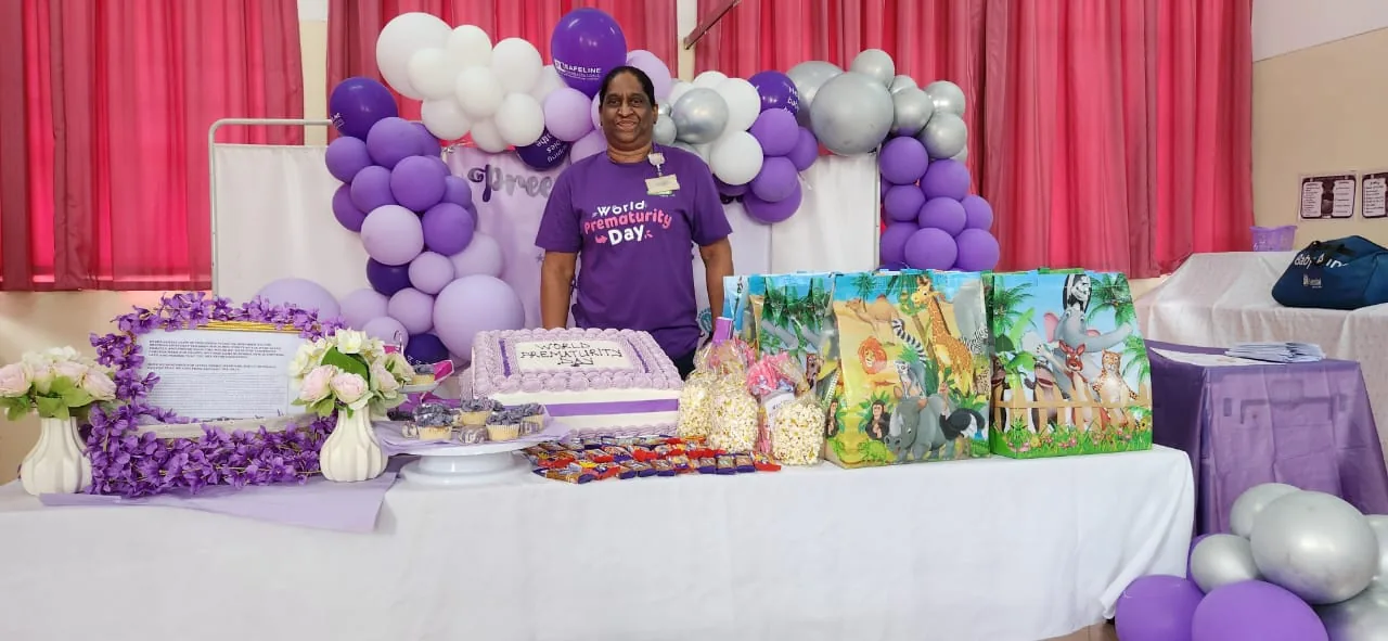 A Nappy Bag Initiative volunteer at a World Prematurity Day event table decorated in purple